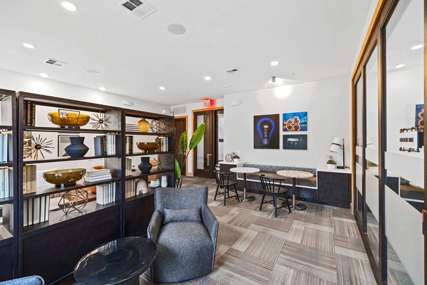 a lounge area with chairs and tables and a bookshelf