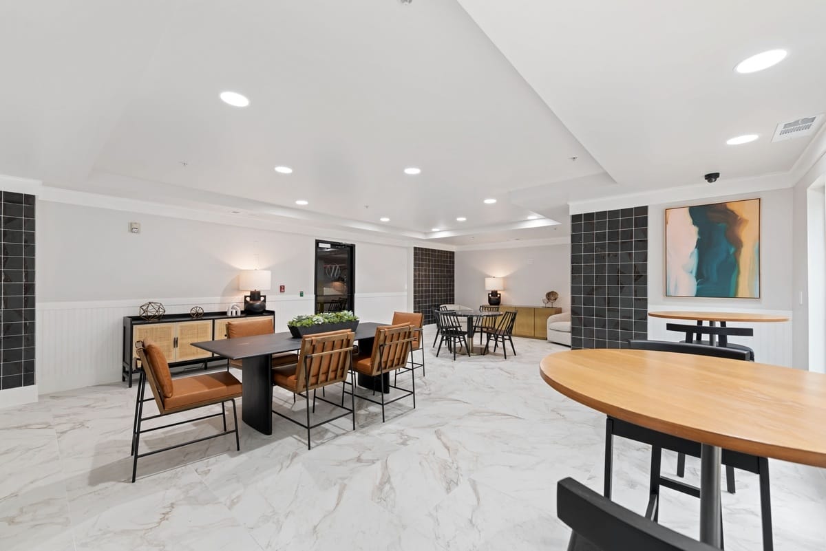 Another angle of the clubhouse with chairs and black coffee tables along with cafe style seating.