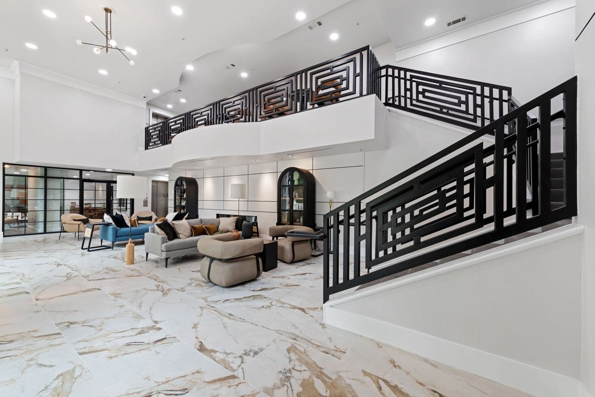 Updated lobby with marble floors, a staircase that wraps upward and comfy seating on the lower level.