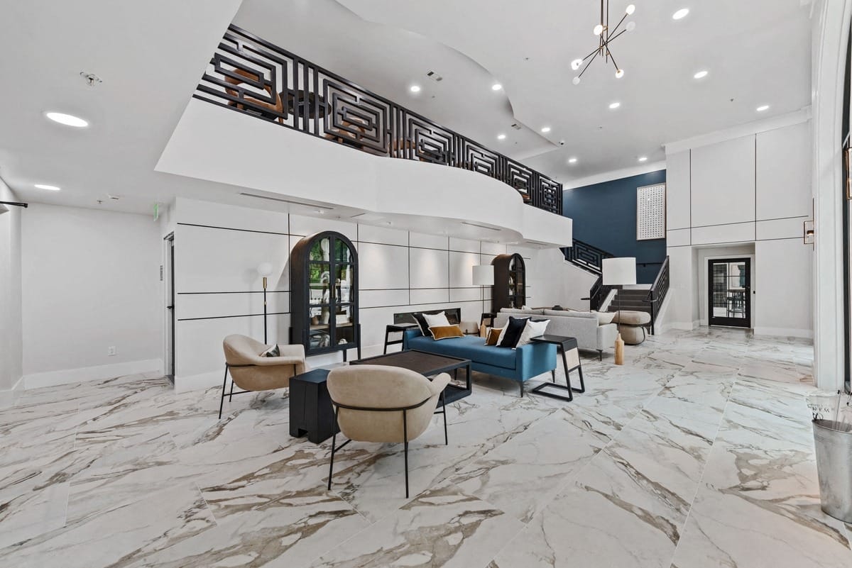 Cozy chairs in a large open space with tables, bookcases and a view of an upper level from below.