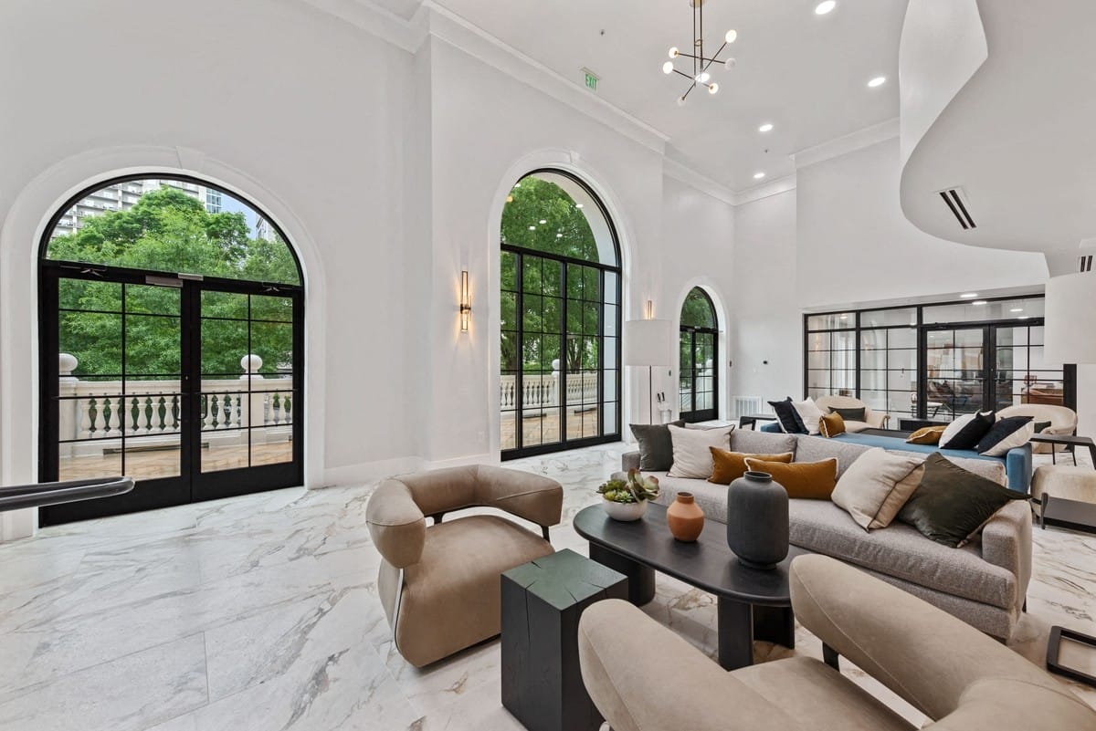 Comfy beige chairs with black coffee tables against a marble floor.