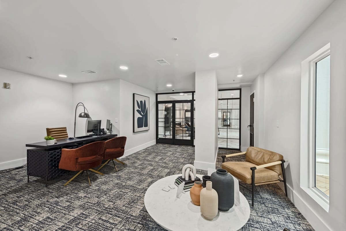 An office with desk, two chairs near a coffee table with another chair.