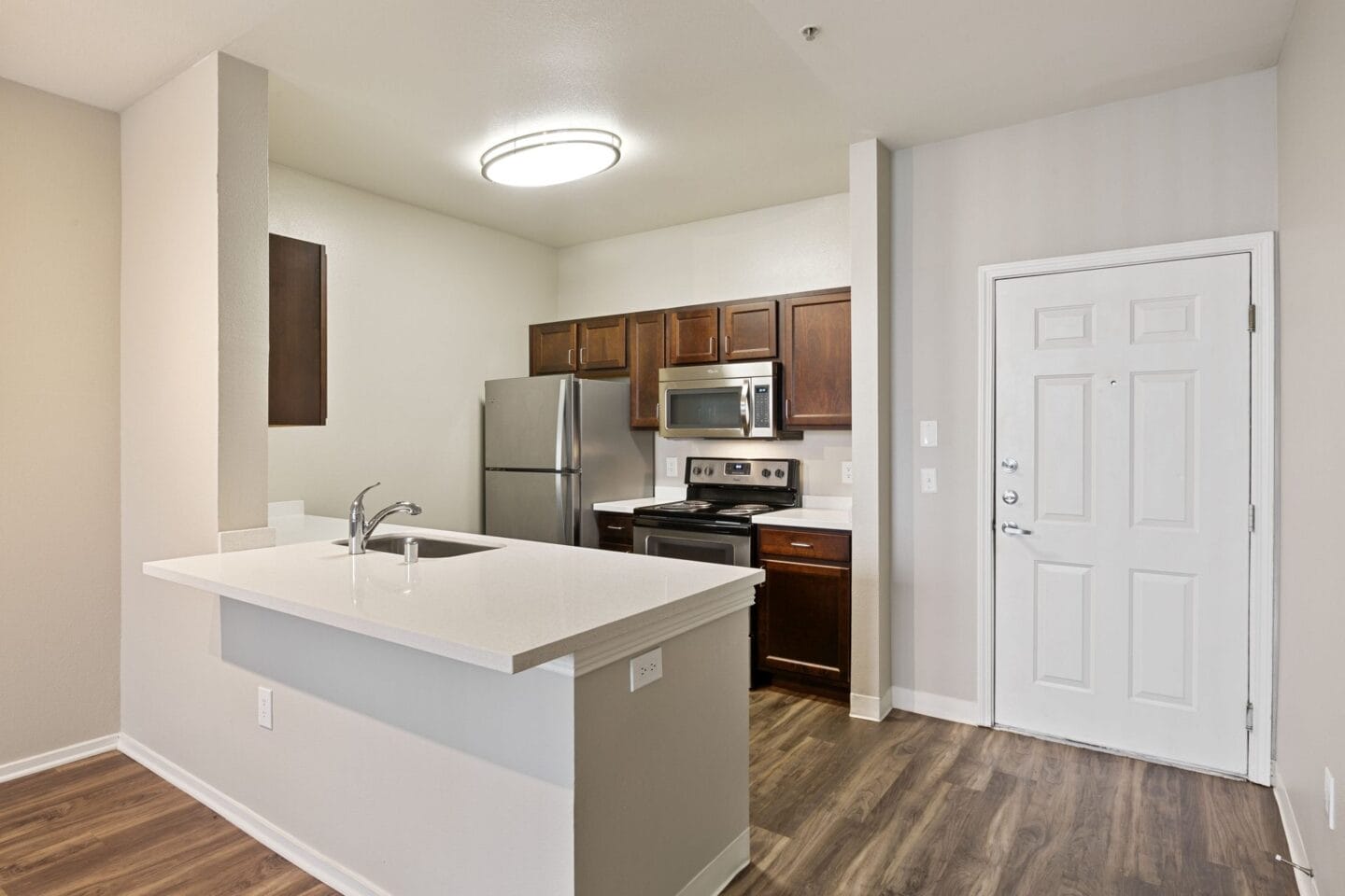 a kitchen with a white counter top and a stainless steel refrigerator