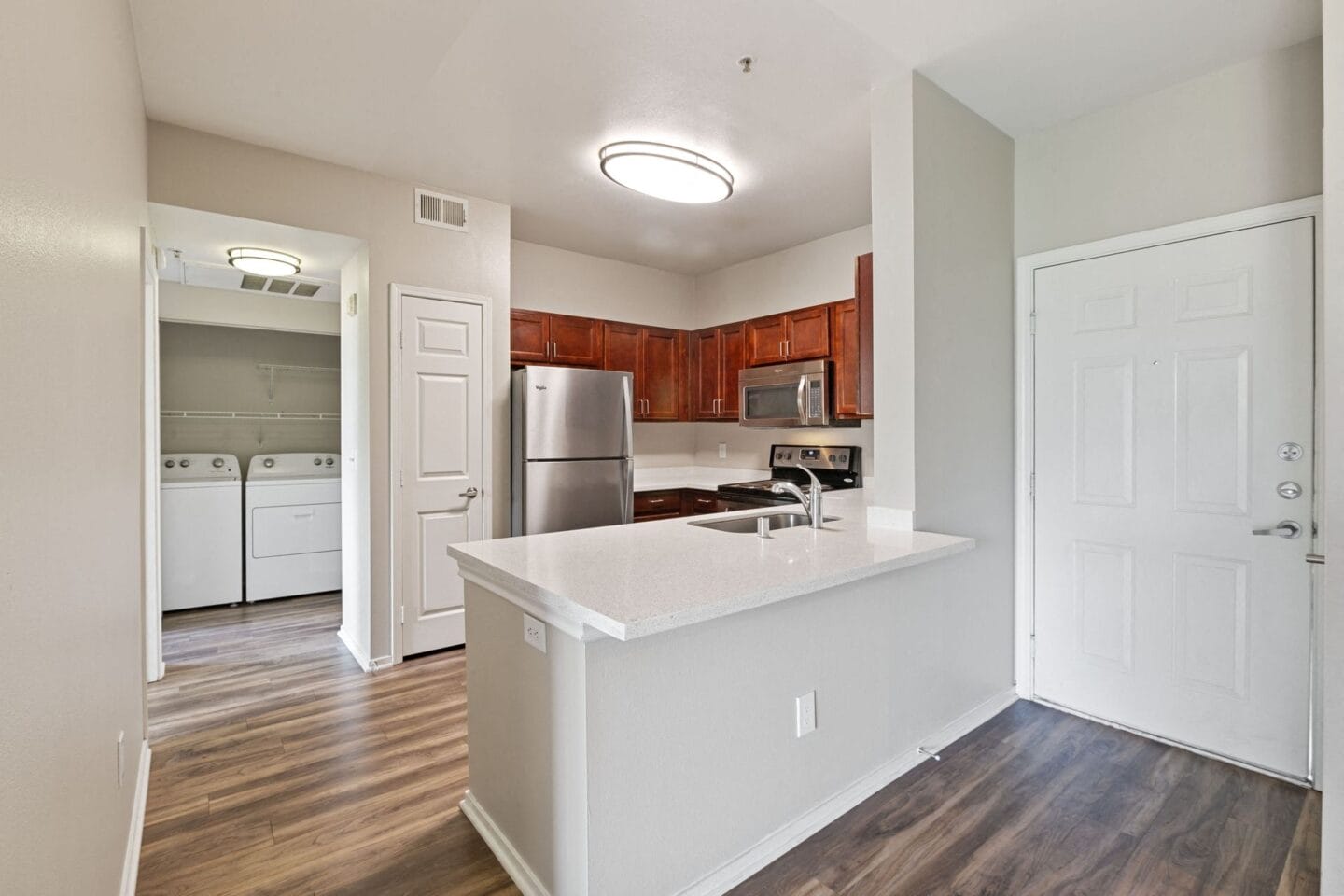 an empty kitchen with a white counter top and a refrigerator