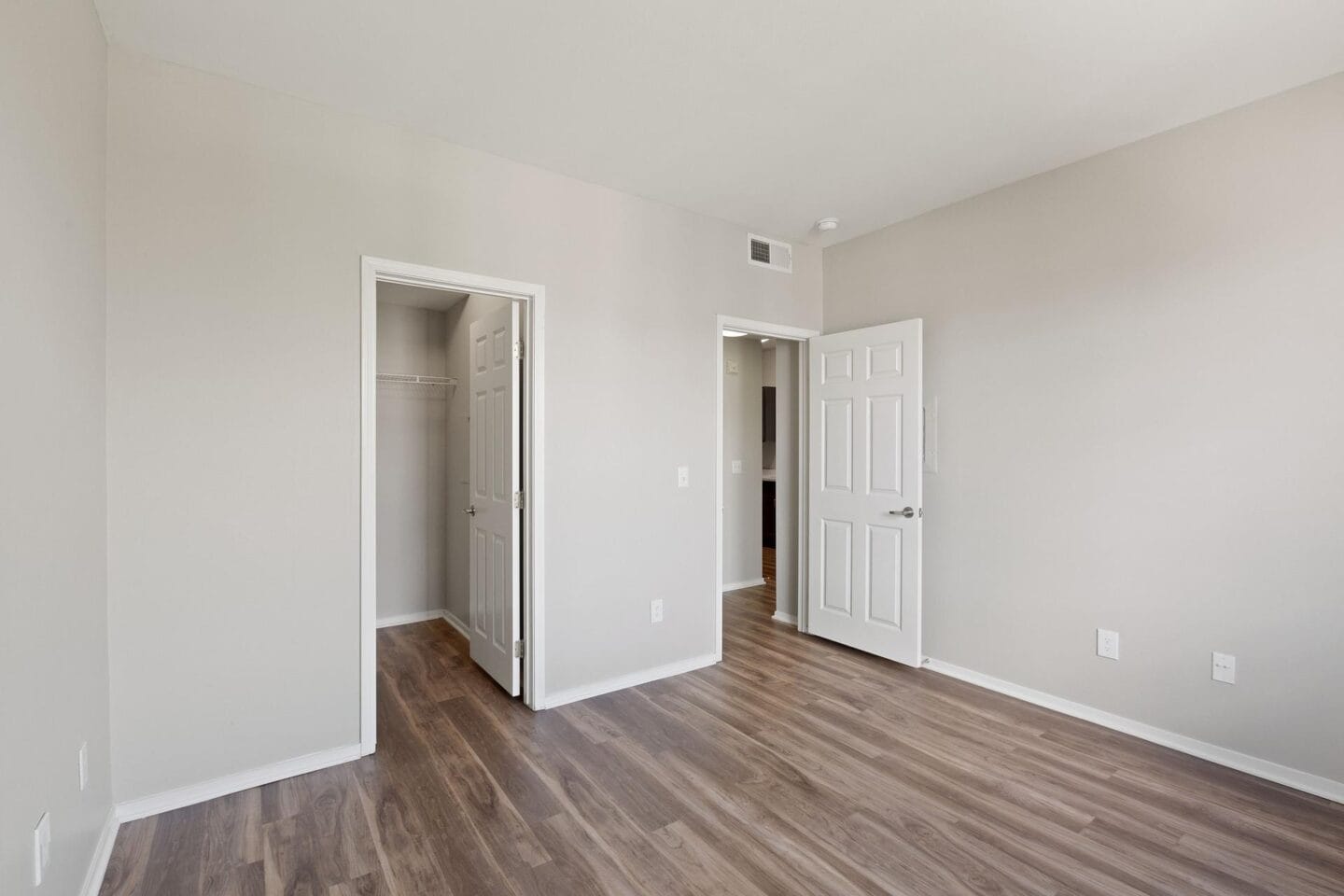 the living room of an apartment with white walls and wood flooring