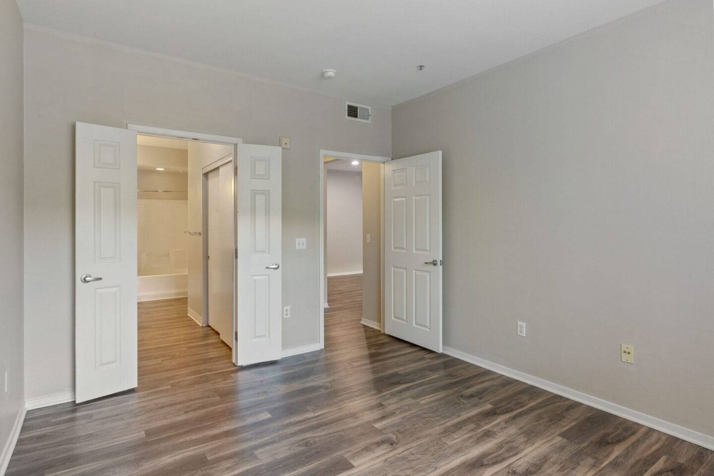 the living room and dining room of an apartment with white doors and wood floors