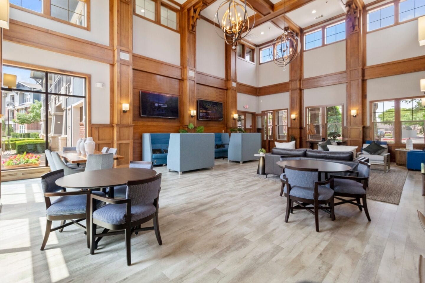 a large lobby with tables and chairs and large windows