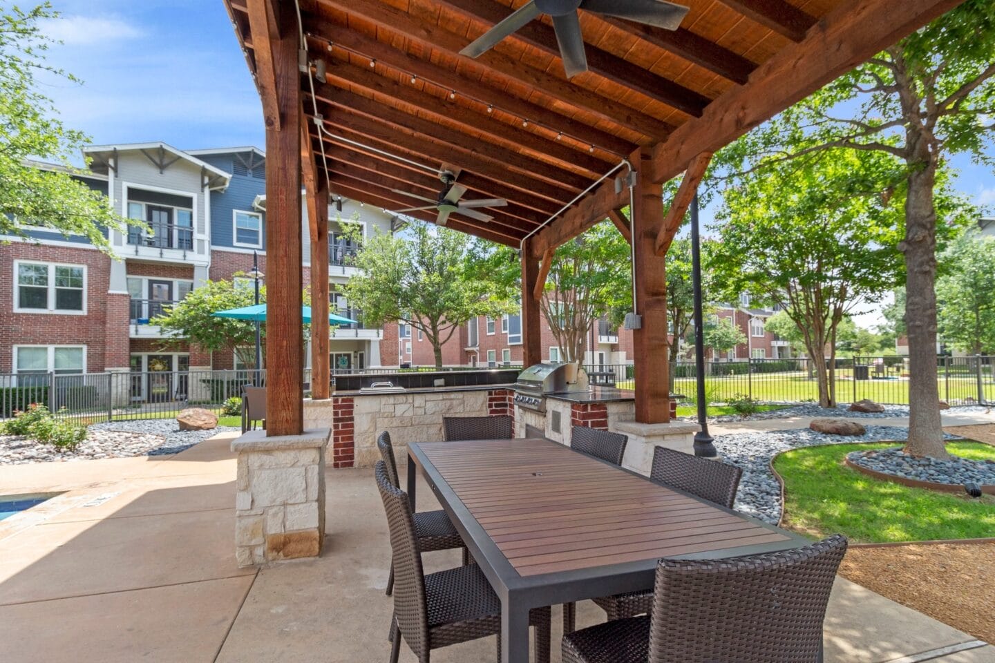 a patio with a table and chairs under a wooden pavilion