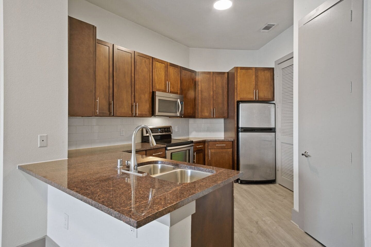 Kitchen with a granite counter top and a sink at The Monterey by Windsor, Dallas, Texas