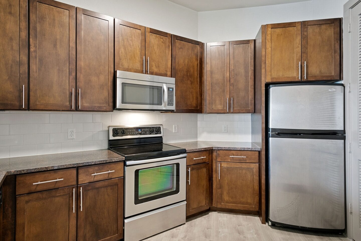 Kitchen with wooden cabinets and appliances and a stainless steel refrigerator at The Monterey by Windsor, Dallas, Texas