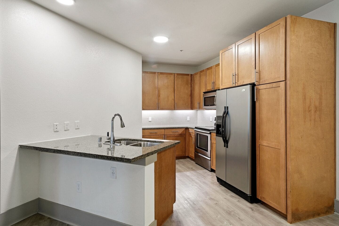 Kitchen with stainless steel appliances and wooden cabinets at The Monterey by Windsor, Dallas, Texas