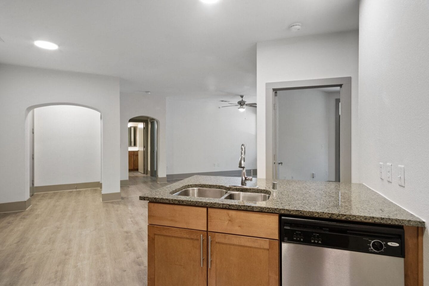 Kitchen and living room of a new home with white walls and granite counter tops at The Monterey by Windsor, Dallas, Texas