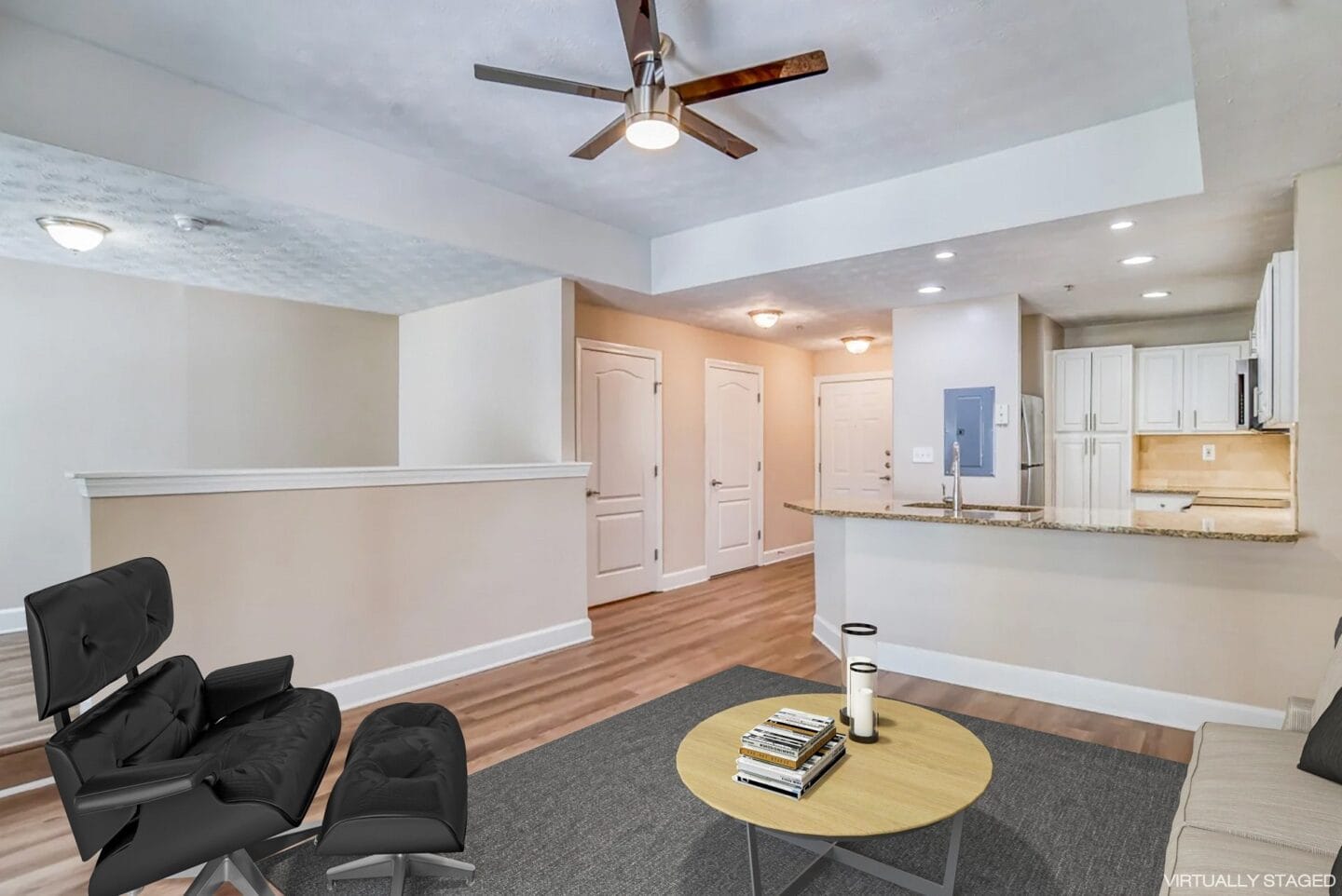 a living room with two black chairs and a ceiling fan