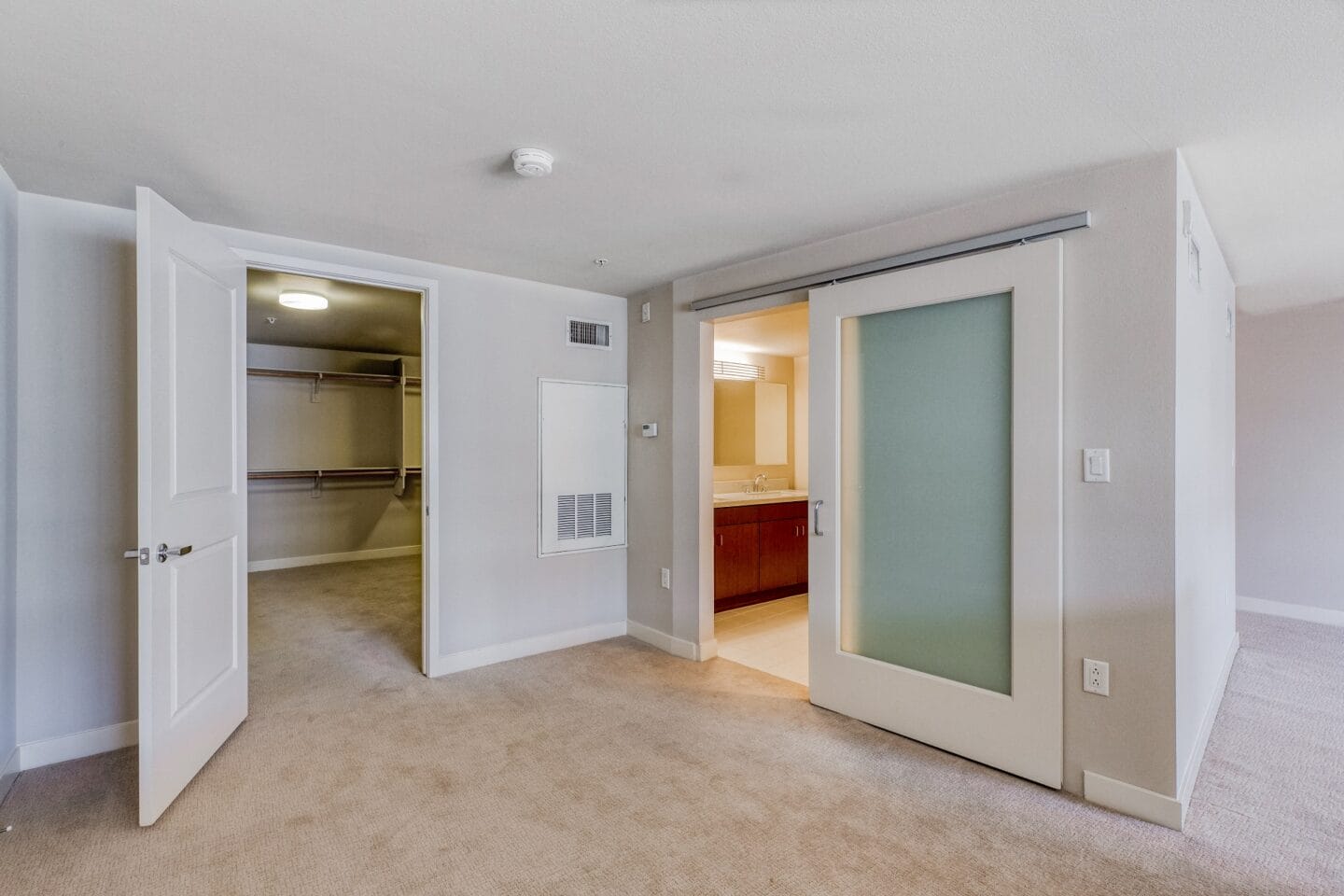 a bedroom with an open door and a bathroom in the background