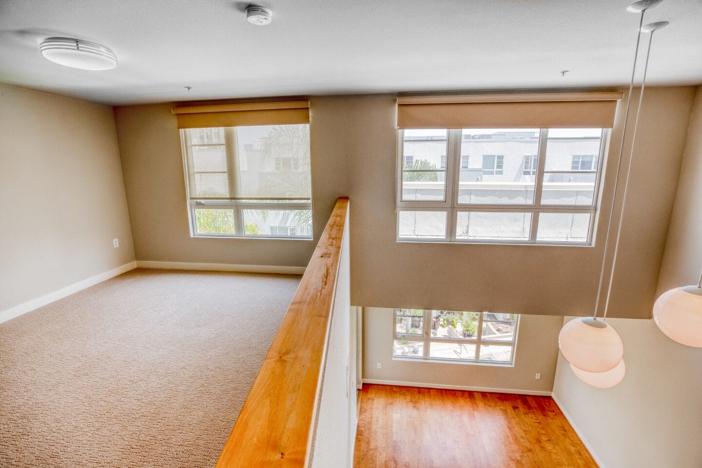 an empty living room with three large windows and a wooden railing