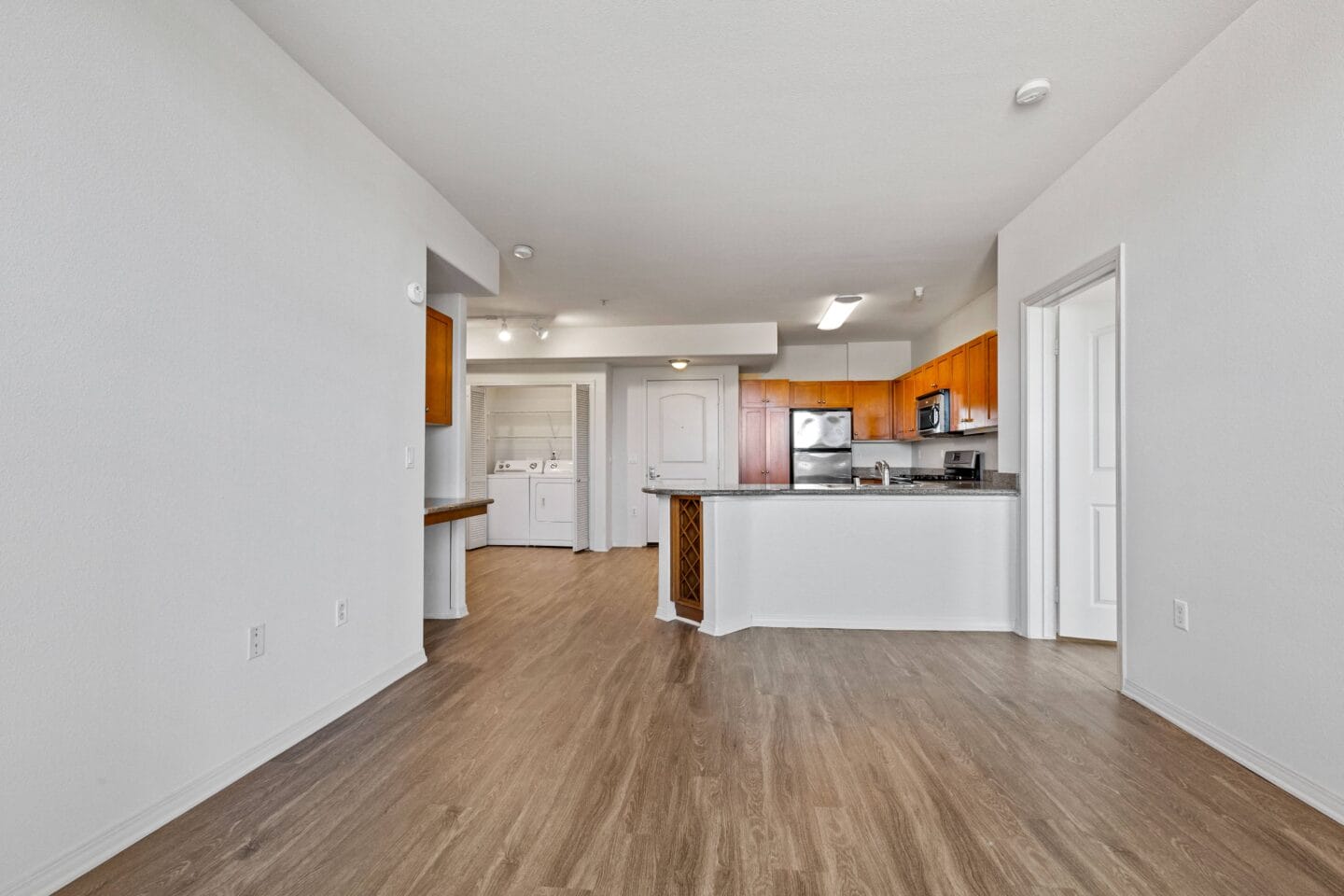 a kitchen and living room with hardwood floors and white walls