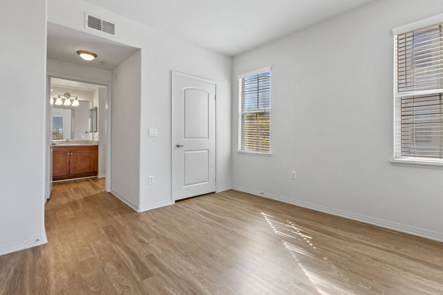 a bedroom with hardwood flooring and a doorway into a bathroom