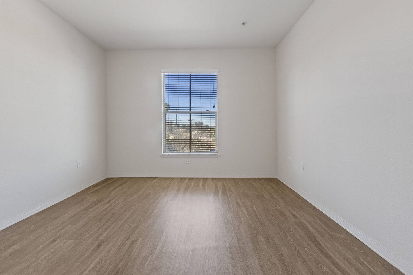 a bedroom with hardwood floors and white walls