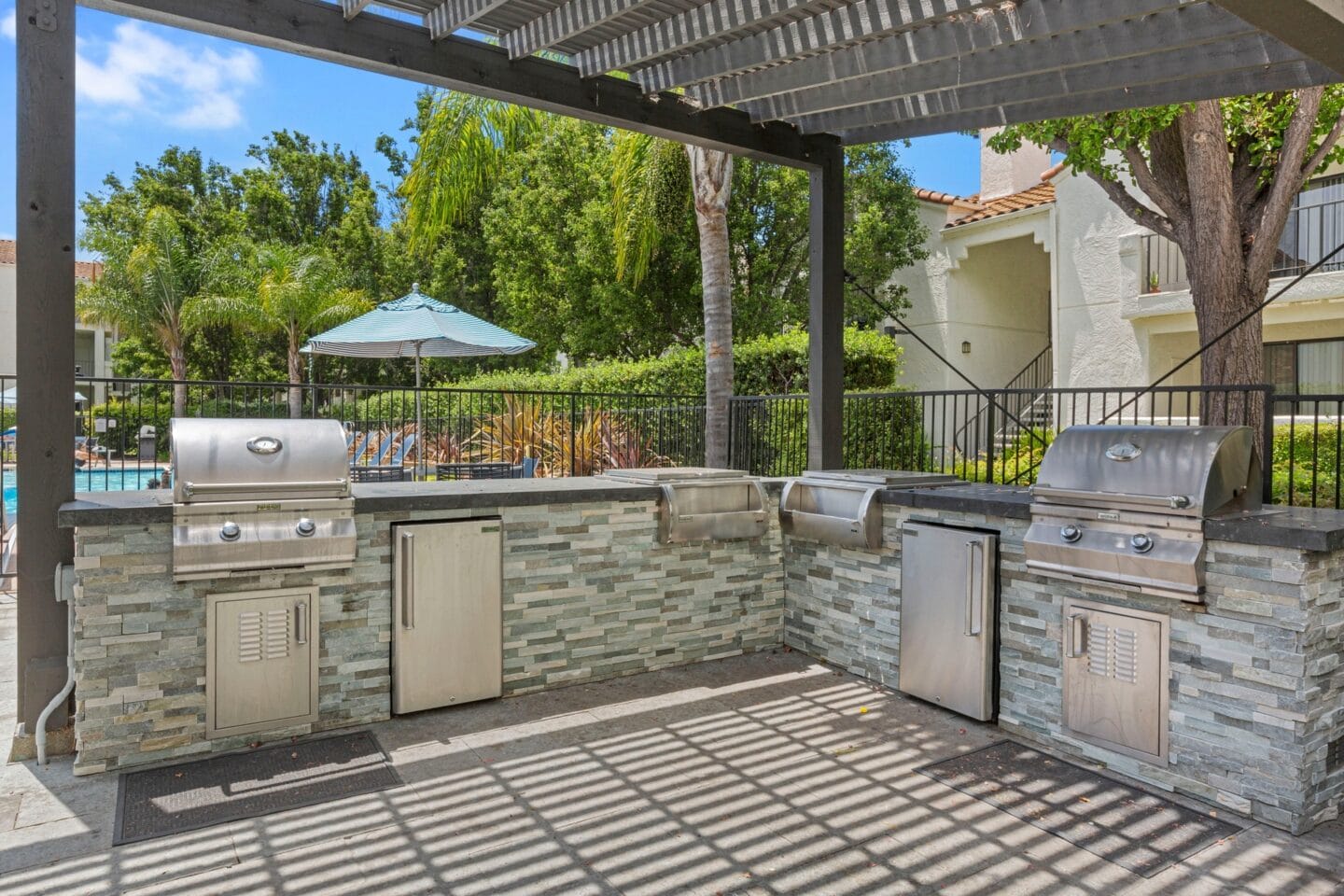 a patio with an outdoor kitchen with stainless steel appliances