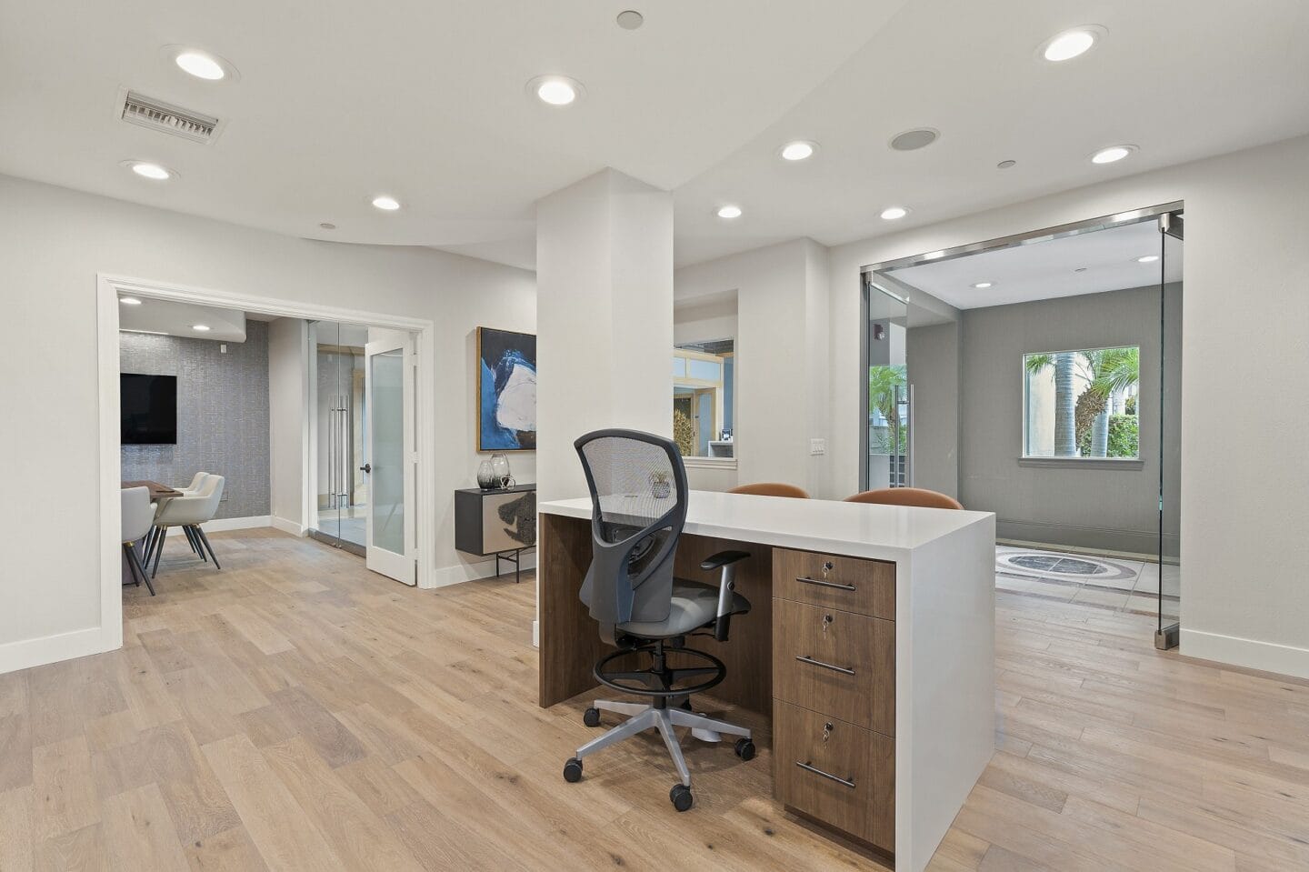 a white office with a desk and a chair in front of a mirror