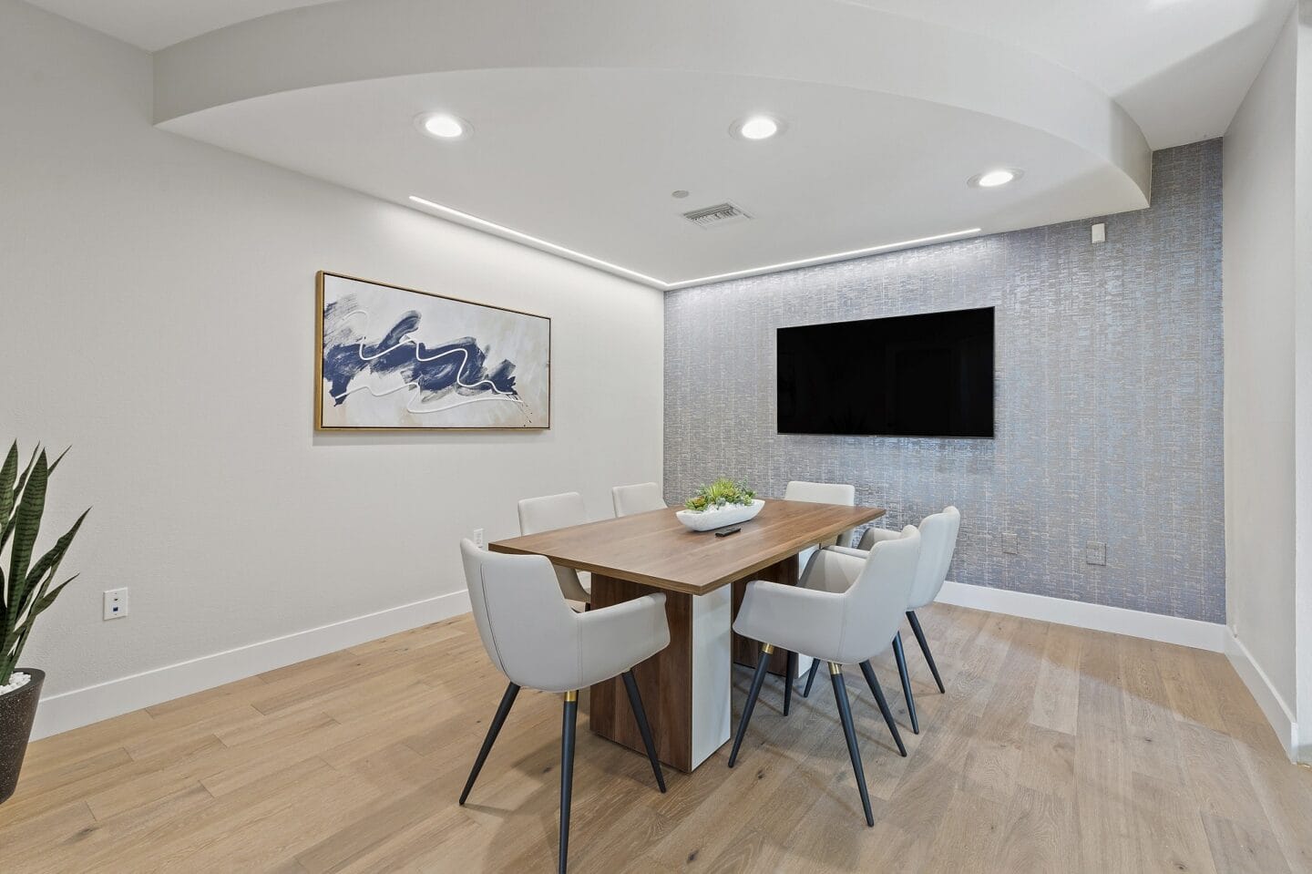 a dining room with a table and chairs and a tv on the wall