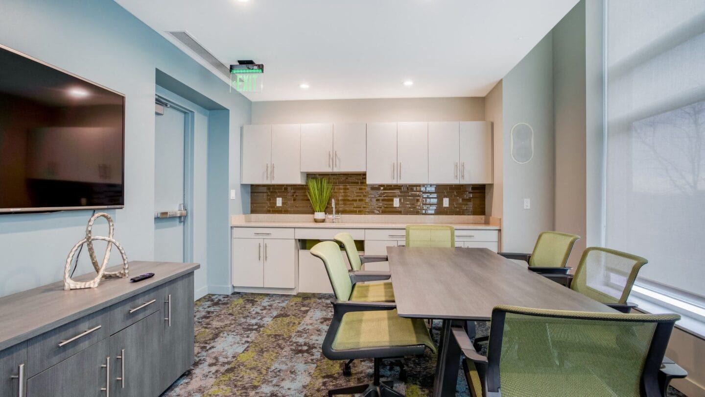 A conference room with a long wooden table and green chairs