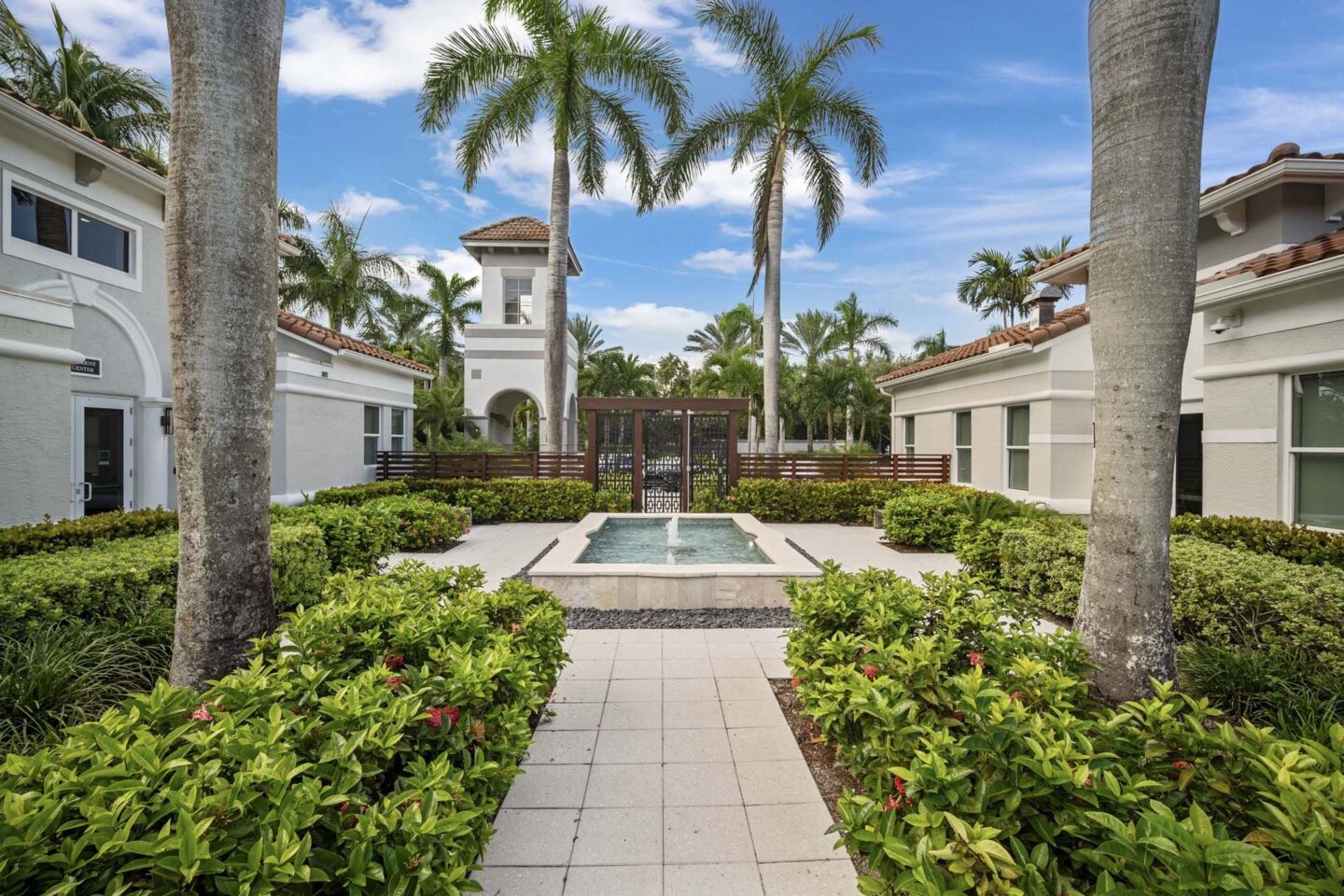 A courtyard with a fountain surrounded by palm trees and bushes at Windsor at Miramar, 3701 SW 160th Ave, Miramar, FL 33027.