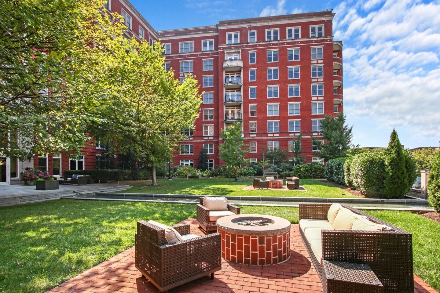 a patio with chairs and a fire pit in front of a building