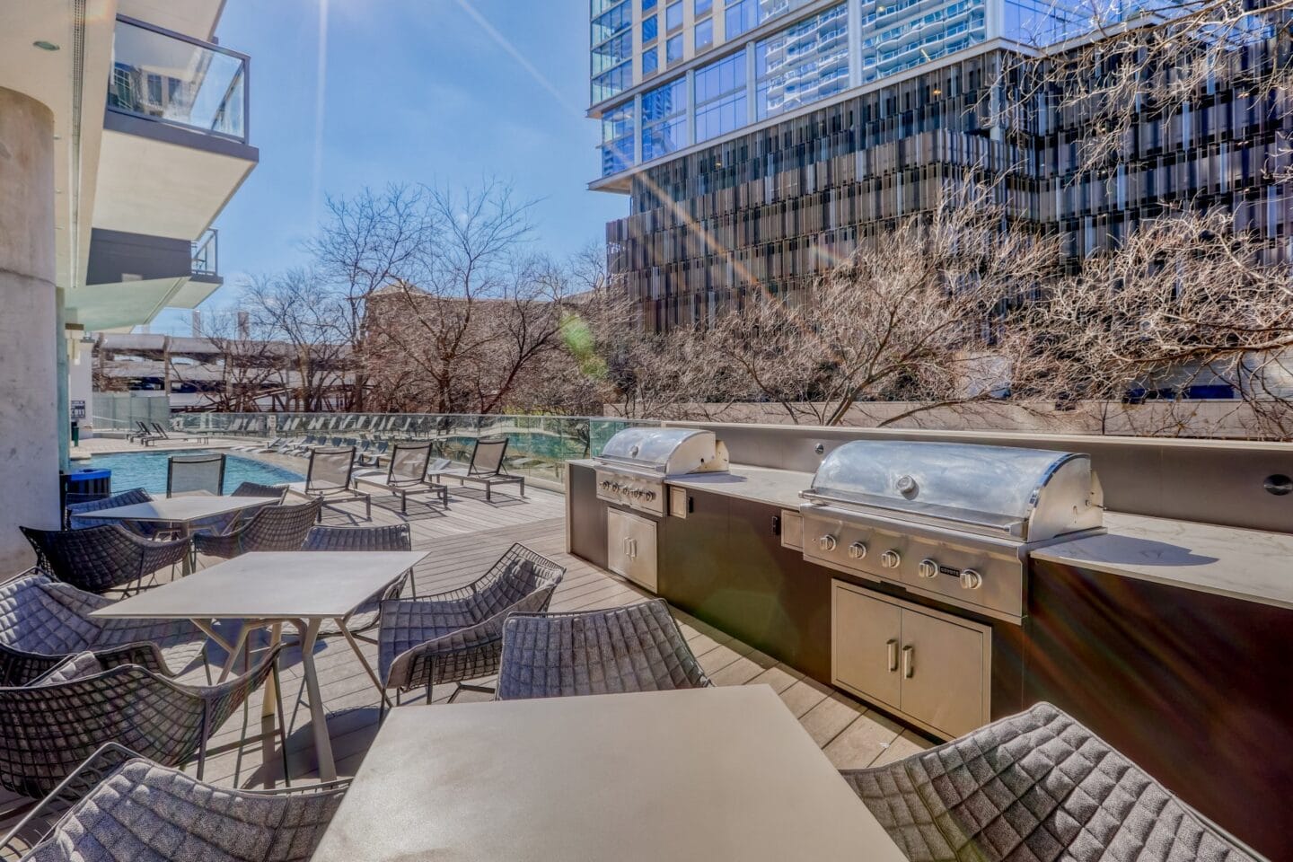 an outdoor patio with barbecue grill and tables and chairs