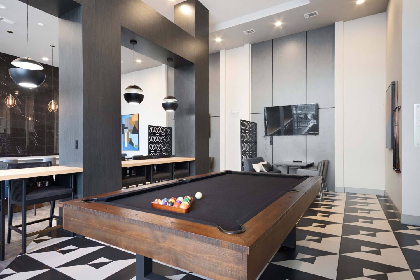 A pool table is in the middle of a room with a black and white checkered floor at Metro West, Texas, 75024.