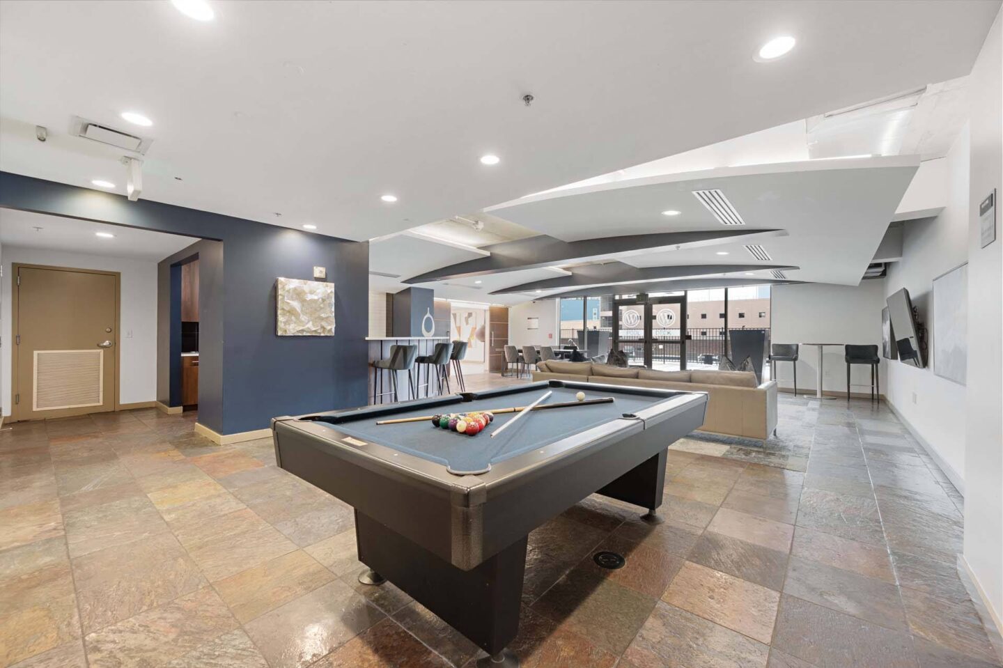 A pool table is in the middle of a room with a blue wall at The Manhattan Tower and Lofts, Denver, 80202.