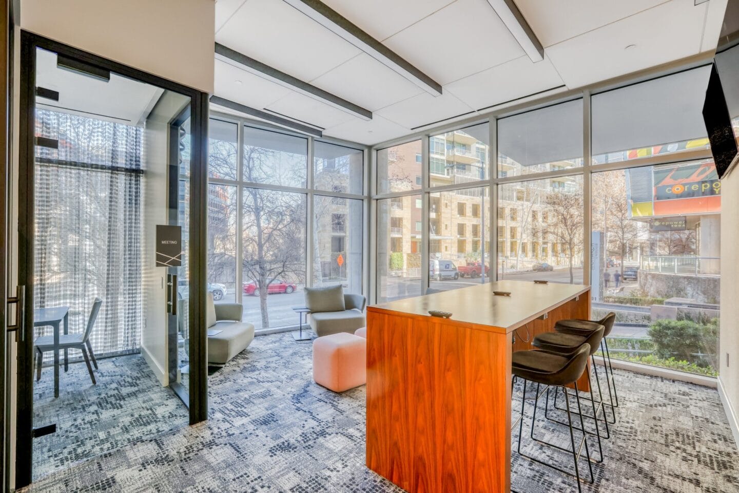 a room with glass walls and a wooden table with black chairs