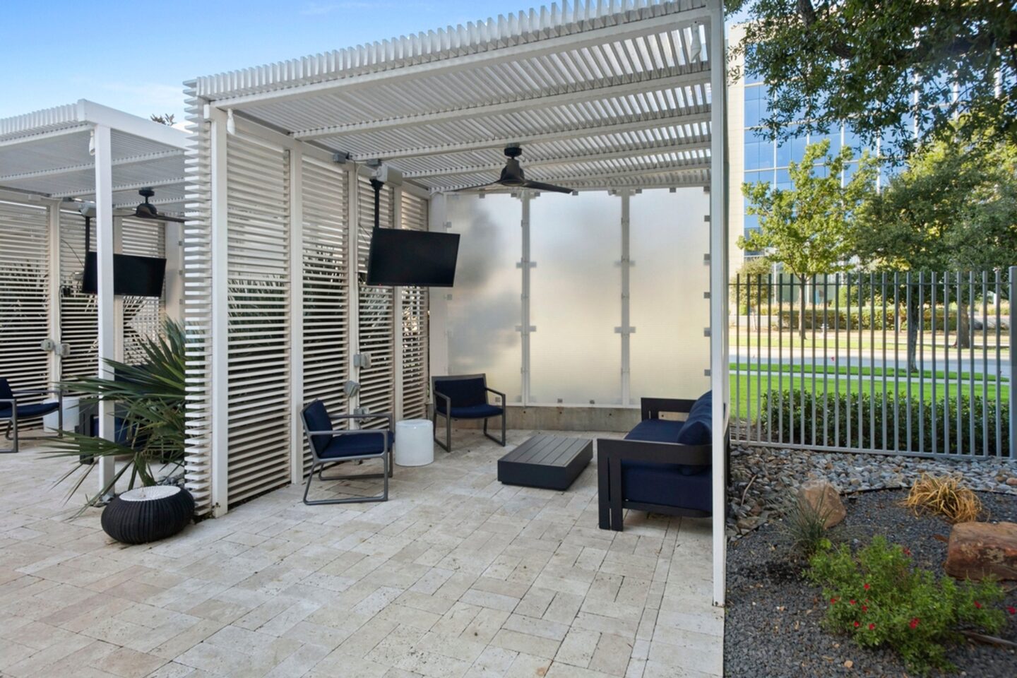 A patio area with a white pergola and black furniture.