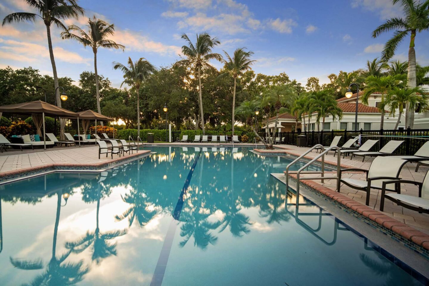 A pool surrounded by palm trees and lounge chairs at Windsor at Miramar, 3701 SW 160th Ave, Miramar, FL 33027.