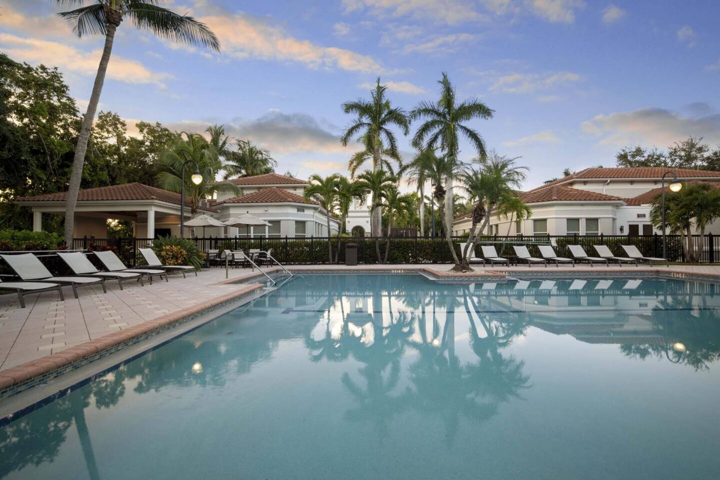 A pool with a reflection of palm trees and a building in the background at Windsor at Miramar, 3701 SW 160th Ave, Miramar, FL 33027.