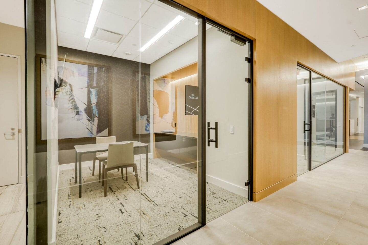 A glass walled conference room with a table and chairs