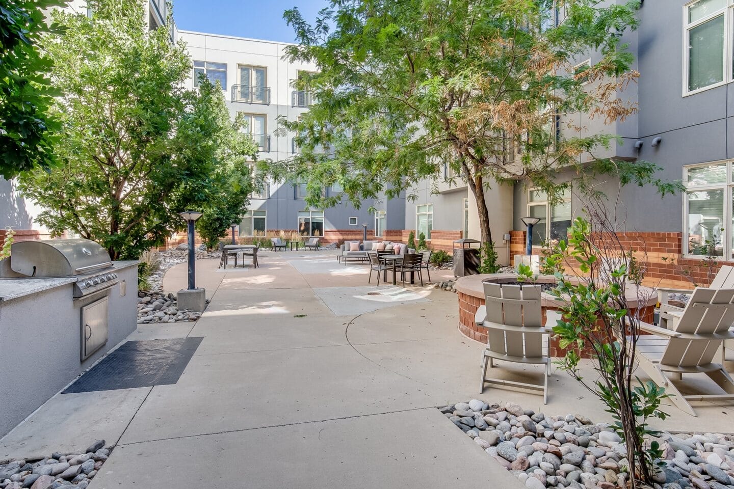 an outdoor patio with trees and chairs and a grill