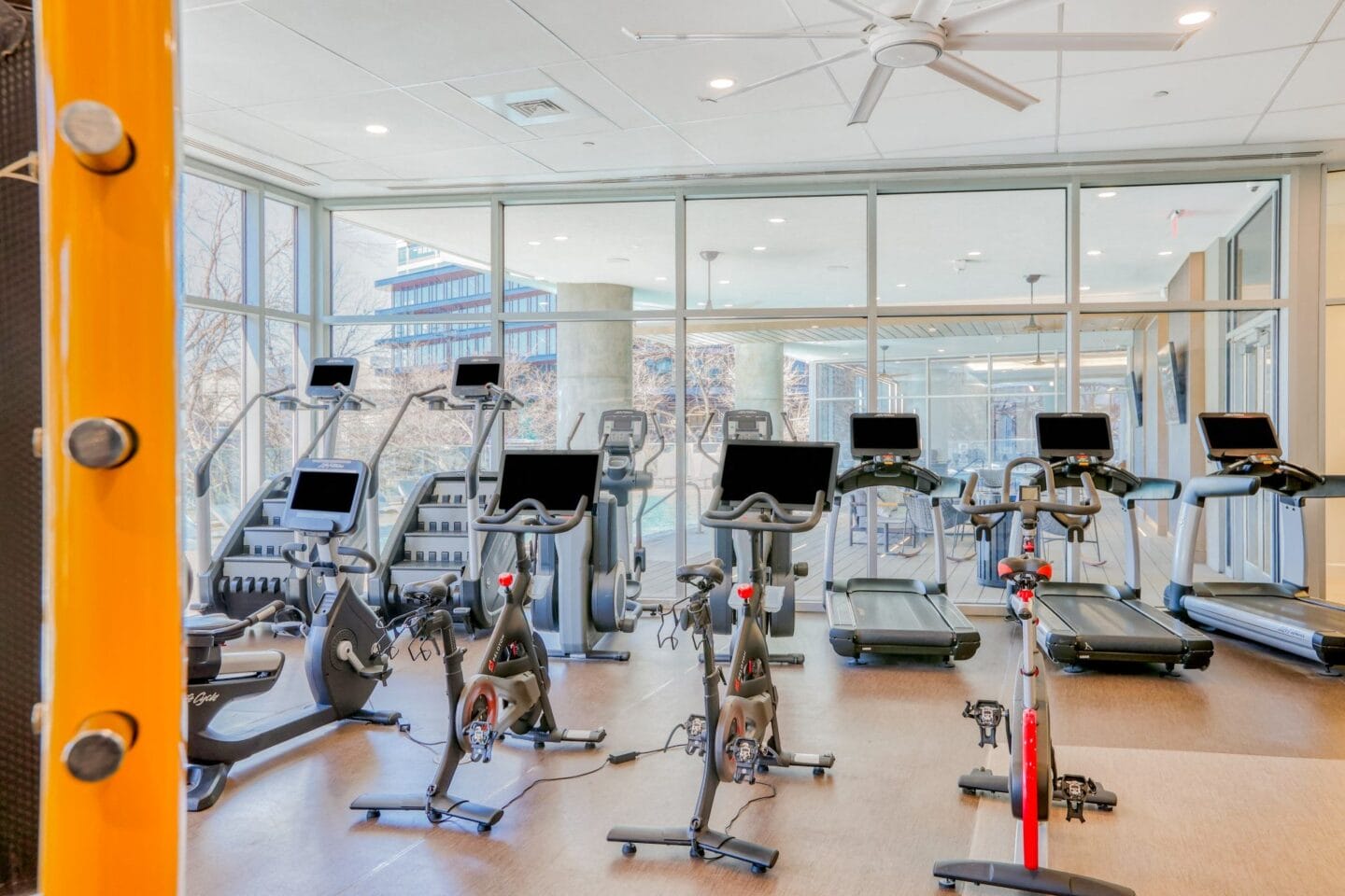 a room filled with lots of cardio equipment and a lot of windows