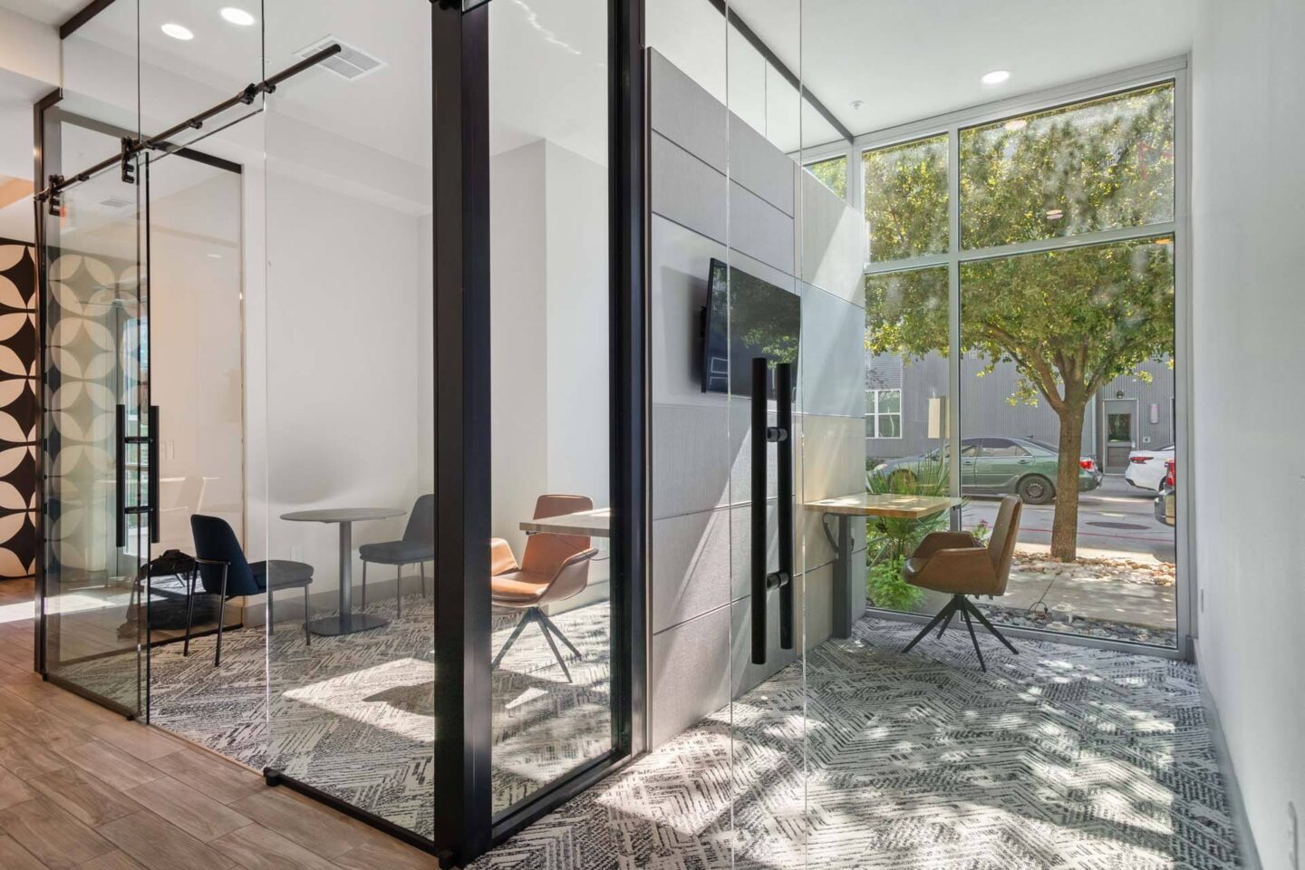 A modern room with glass walls and a TV mounted on the wall at Metro West, Texas, 75024.