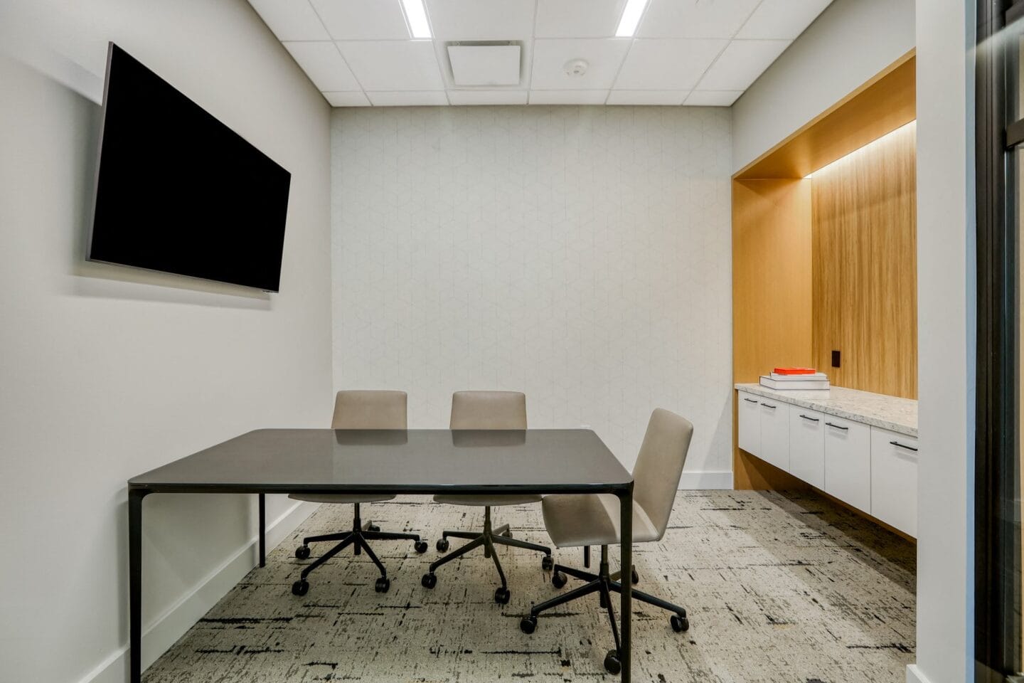 a meeting room with a table and chairs and a tv on the wall