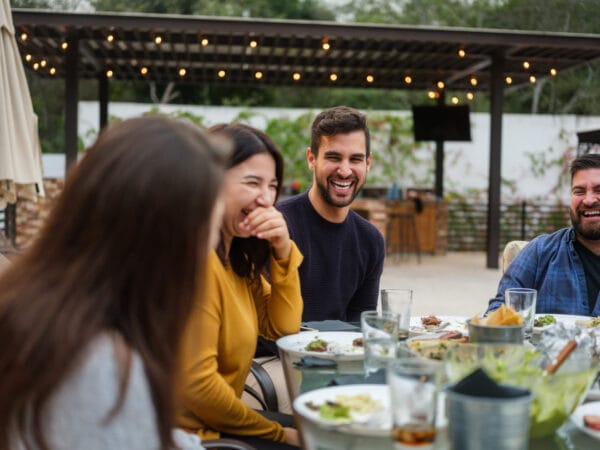 A diverse group of individuals gathered around a table, enjoying a meal together in a warm and inviting setting.