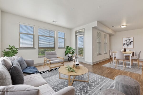 An open living room and dining room with a couch and a table at Windsor at Pinehurst, Lakewood, CO