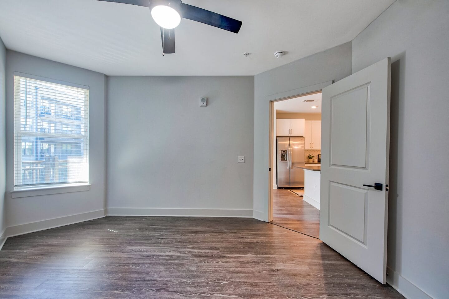 a bedroom with a large window and a ceiling fan