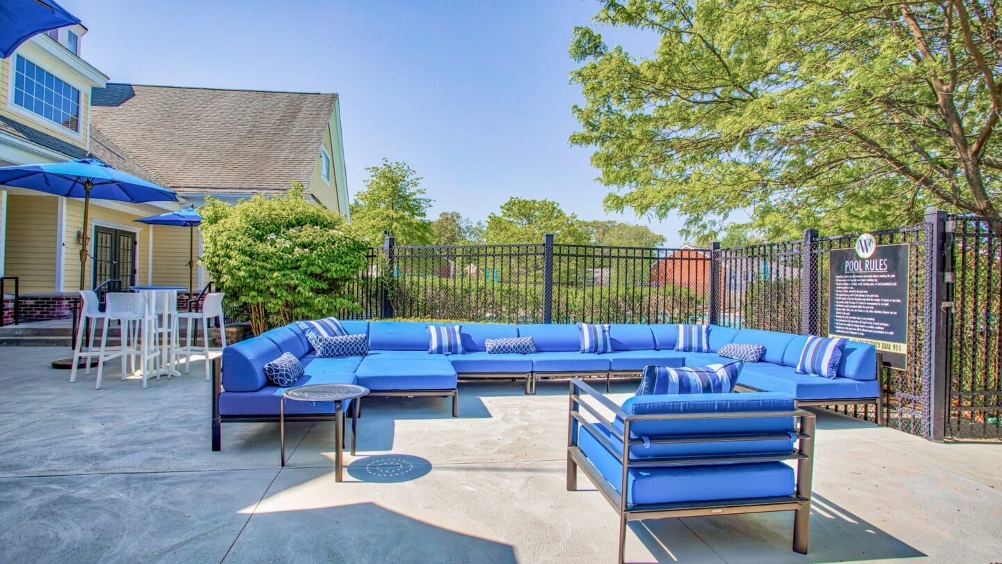 Outdoor patio with blue couches and umbrellas at Windsor Ridge at Westborough, Westborough, MA