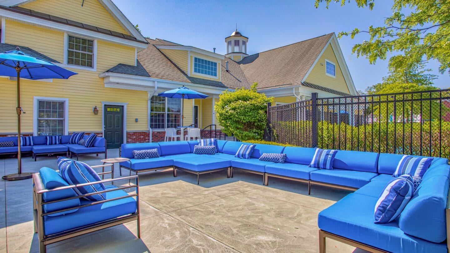 Outdoor patio with blue couches and umbrellas at Windsor Ridge at Westborough, Westborough, MA