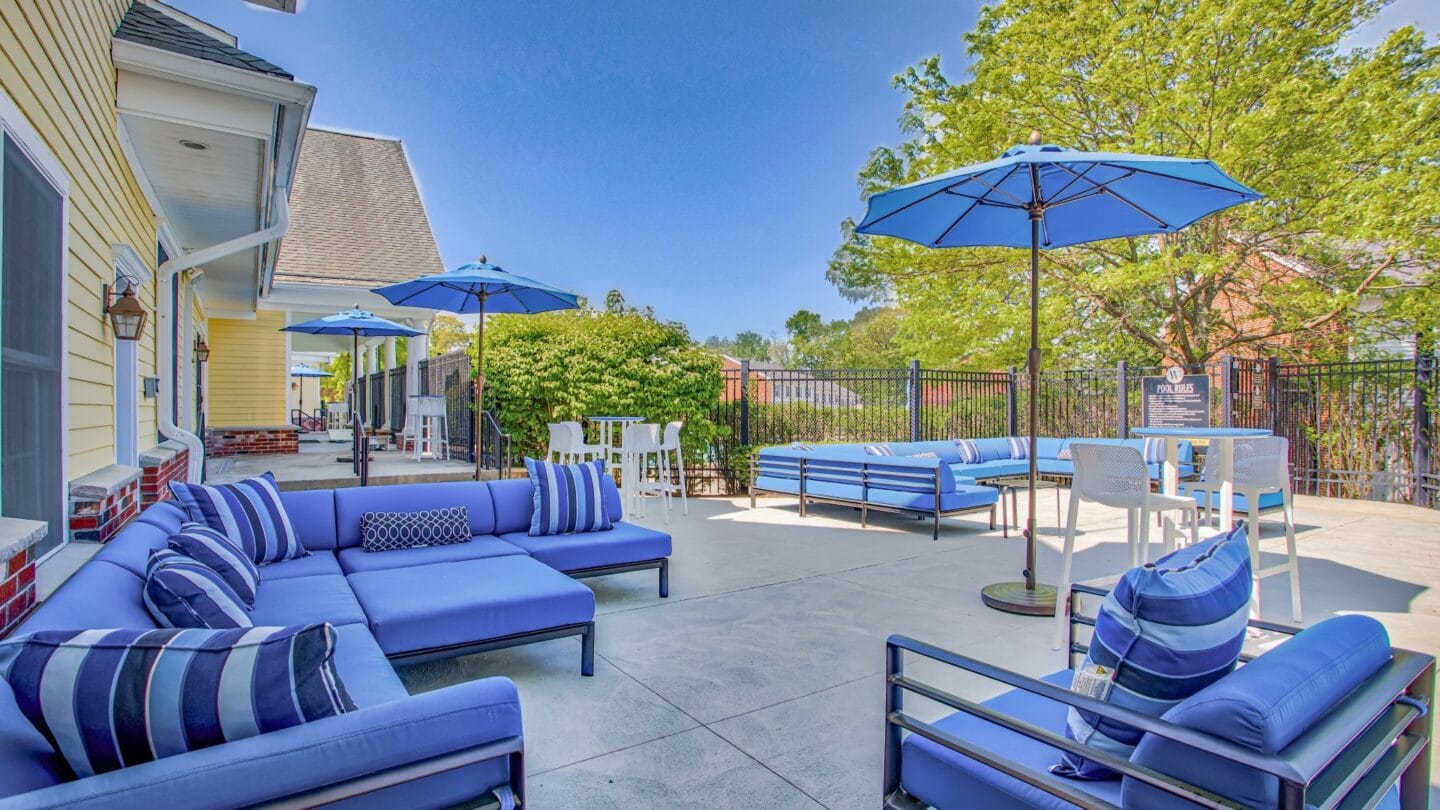 Outdoor patio with blue couches and umbrellas at Windsor Ridge at Westborough, Westborough, MA