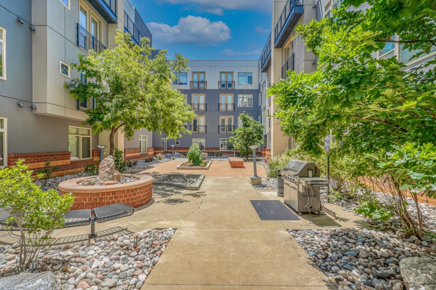 A courtyard with trees and a grill at The District, Denver, CO