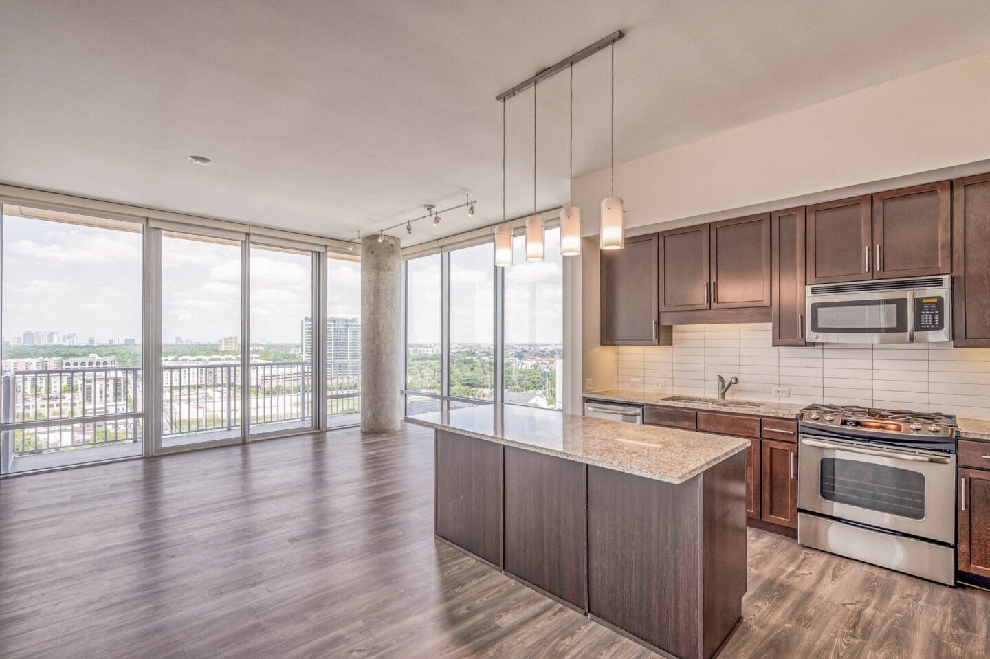 Kitchen and living room with wood flooring and large windows at The Sovereign at Regent Square, 3233 West Dallas, Houston, TX