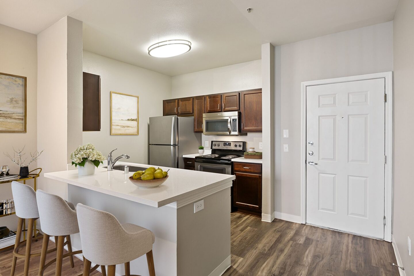 A kitchen with white countertops and wooden cabinets at Pavona Apartments by Windsor, 760 N. 7th Street San Jose, CA 95112.