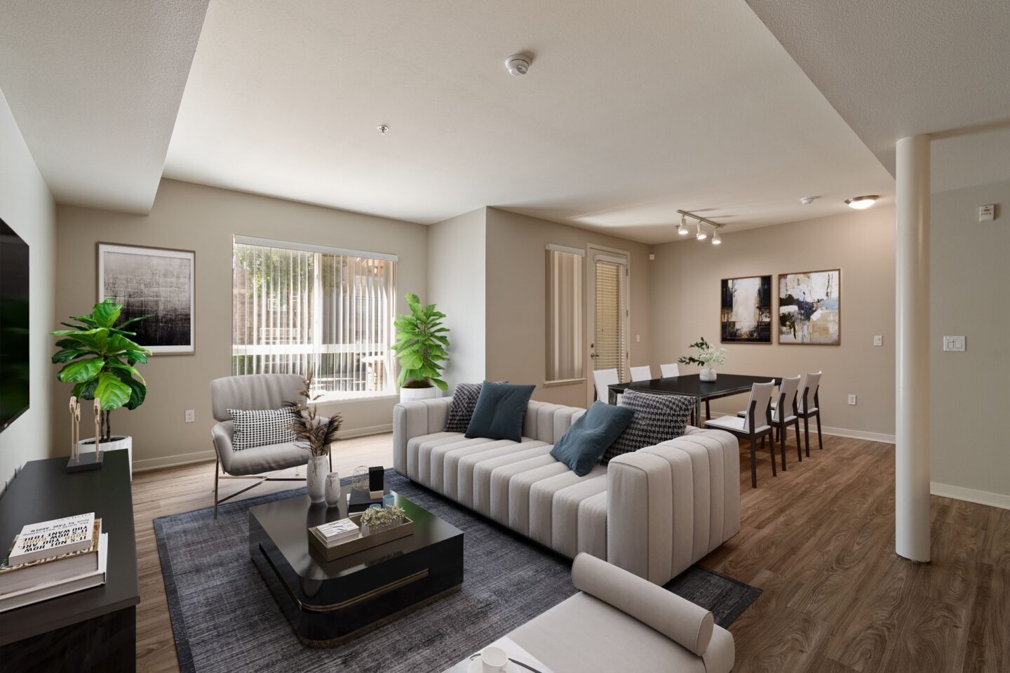 A modern living room with a grey sofa, a black coffee table, and a large window with blinds.